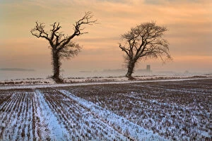 Snow on stubble field at dusk with Southrepps Church in the background, North Norfolk