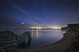 Blue Gallery: Stars and Milky Way over Durdle Door and the Jurassic Coast, with the lights of Weymouth