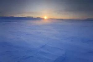 Sun low on the horizon with wind blowing snow, Agardh-bukta, Spitsbergen, Svalbard