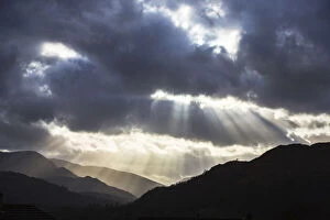Sun rays shining through clouds onto Loughrigg Fell and hills of the Lake District