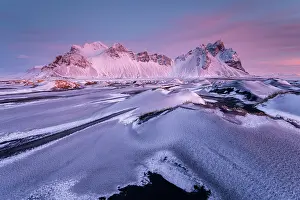 Vestrahorn mountain and sand dunes covered in snow at sunrise. Stokksnes Peninsula, Iceland. January, 2024