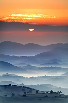 View of country house, fields and mountains with sun rising in the mist, Montellano