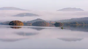 Morning Prints: View over Derwentwater, towards Friars Crag in autumn colour and morning mist with lone rower
