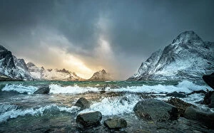 Blue Waters Collection: Winter storm clouds gathering along rocky shore surrounded by snow-covered mountains
