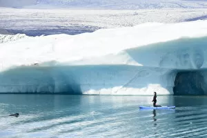 Iceberg Gallery: Woman paddling alongside curious Harbor seal (Phoca vitulina). Jokulsarlon Glacier Lagoon, Iceland